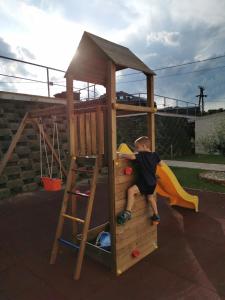 Młody chłopiec wspina się na drewniany domek zabaw w obiekcie Life Apartman Orfű w mieście Orfű