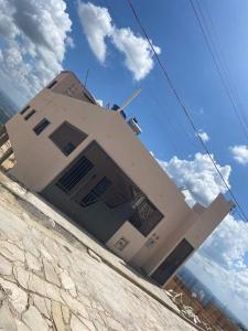 a building in front of a blue sky with clouds at CASA TOCA FURADA in São Thomé das Letras +4 photos