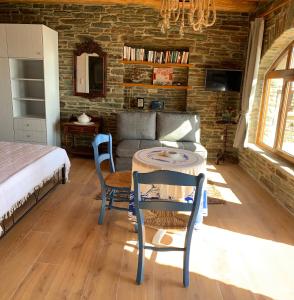 ein Wohnzimmer mit einem Sofa, einem Tisch und Stühlen in der Unterkunft ΠΕΤΡΙΝΟ στην Άνδρο in Agia Eleousa
