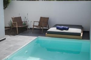 a bed and chairs next to a swimming pool at Hygge Suites in Hersonissos