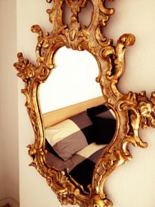 an ornate gold mirror hanging on a wall at B&B Il Cortile in Vercurago