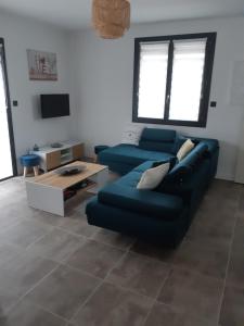 een woonkamer met een blauwe bank en een tv bij Appartement fonctionnel proche du centre ville in Narbonne
