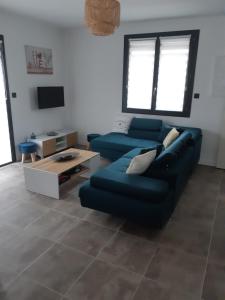 salon z niebieską kanapą i telewizorem w obiekcie Appartement fonctionnel proche du centre ville w mieście Narbona