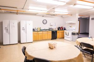 a kitchen with white appliances and tables and chairs at Delta Lodge in Delta Junction