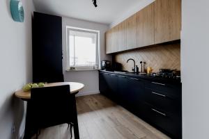 cocina con armarios negros y suelo de madera en Apartament Aura, en Biała Podlaska