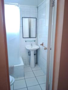 a white bathroom with a sink and a mirror at Aquamarina Apart Hotel in Viña del Mar