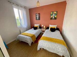 2 łóżka w pokoju z pomarańczowymi ścianami w obiekcie la Casa d'Olianna - Jolie Maison / Jeux / Grand jardin w mieście Villeny