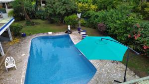 a blue pool with an umbrella in a yard at Maison de vacances avec piscine et accès plage de sable blanc in Punaauia