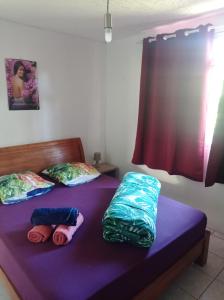 two beds in a room with purple sheets and pillows at Maison de vacances avec piscine et accès plage de sable blanc in Punaauia