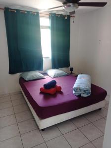 - une chambre avec un lit violet et des rideaux bleus dans l'établissement Maison de vacances avec piscine et accès plage de sable blanc, à Punaauia