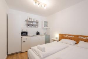 a white bedroom with a bed and a kitchen at Kékmadaras Vendégház Tihany in Tihany