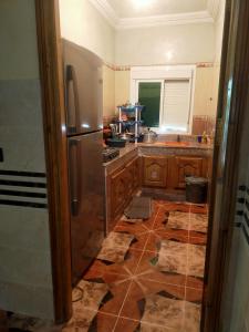 a kitchen with wooden cabinets and a refrigerator at دار الضيافة تازكة Maison d'hôtes Tazekka in Taza