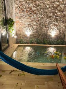a pool of water with a hammock in a room at Casa Coco in Mérida