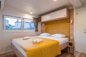 a bedroom with a bed with two towels on it at Giardino Sukošan - new mobile houses in olive garden, EV plug-in station in Sukošan