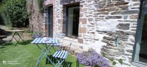 2 chaises et une table en face d'un bâtiment en pierre dans l'établissement Maison d'hôtes KerCalow, Chambres d'hôtes, à Pleine-Fougères