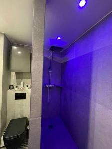 a purple bathroom with a shower with a toilet at The Prism ,studio on the top floor with a balcony in Neuilly-sur-Seine