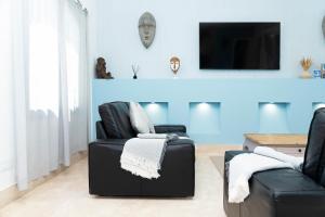 een woonkamer met twee zwarte stoelen en een tv bij Villas Veaco Bahiazul with private pool in Corralejo