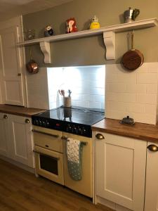 a kitchen with white cabinets and a stove top oven at Traditional Cottage in Harbour Town of Watchet in Watchet