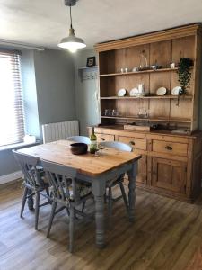 a dining room table with chairs and a wooden cabinet at Traditional Cottage in Harbour Town of Watchet in Watchet