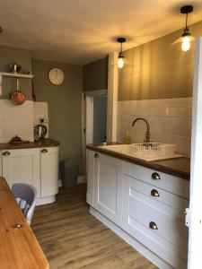 a kitchen with white cabinets and a sink at Traditional Cottage in Harbour Town of Watchet in Watchet