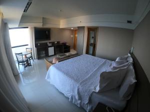 a bedroom with a white bed and a living room at Tropical Executive Hotel in Manaus