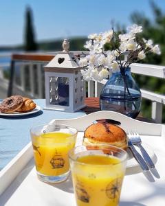 einen Tisch mit zwei Gläsern Orangensaft und einem Sandwich in der Unterkunft Villa Ana Apartments in Molunat