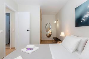 een witte slaapkamer met een wit bed en een spiegel bij sofia's apart 4u (114) in Glyfada