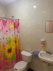 a bathroom with a toilet and a flower shower curtain at Palmas in Cuernavaca