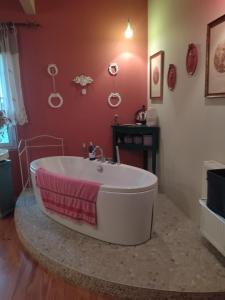 a bath tub in a bathroom with a red wall at Comme chez vous "pour 4 personnes" in Puycornet