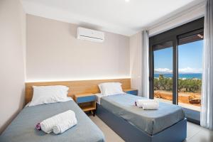 two beds in a room with a view of the ocean at Luxury Villas In Nopigia With A Private Pool - Isabel Artemis in Nopíyia