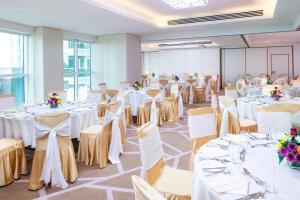 um salão de banquetes com mesas e cadeiras brancas em Four Points by Sheraton Sharjah em Sharjah