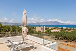 eine Terrasse mit einem Sonnenschirm und Stühlen auf einem Balkon in der Unterkunft Luxury Villas In Nopigia With A Private Pool - Isabel Artemis in Nopíyia