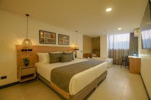 a bedroom with a large bed and a bathroom at First Class Hotel in Medellín