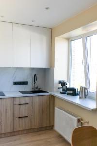 a kitchen with white cabinets and a sink and a window at Windy City apartments in Liepāja +15 photos