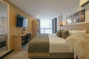 a bedroom with a bed and a desk and a television at First Class Hotel in Medellín