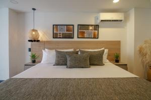 a bedroom with a large white bed with pillows at First Class Hotel in Medellín