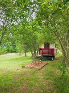 a red and yellow trailer with a picnic table in a field at La roulotte Couzotte in Couze-et-Saint-Front +5 photos