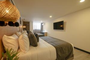 a bedroom with a bed with pillows and a television at First Class Hotel in Medellín