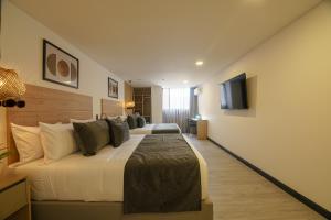 a hotel room with two beds and a flat screen tv at First Class Hotel in Medellín