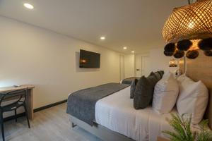 a bedroom with a bed and a desk with a television at First Class Hotel in Medellín