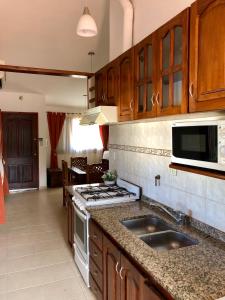 a kitchen with wooden cabinets and a stove top oven at Casa La Quinta in Villa Carlos Paz