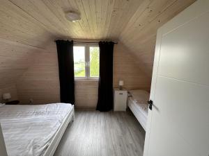Kleines Zimmer mit einem Bett und einem Fenster in der Unterkunft Domki u Karola in Rewal