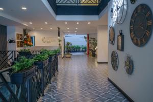 a hallway with plants and clocks on the wall at First Class Hotel in Medellín