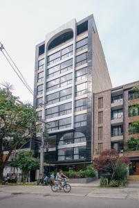 a person riding a bike in front of a building at First Class Hotel in Medellín