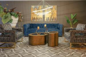 a living room with a blue couch and two chairs at First Class Hotel in Medellín