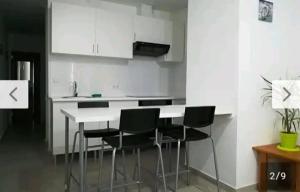 kuchnia z białym blatem i czarnymi krzesłami w obiekcie Corralejo city beach w Corralejo
