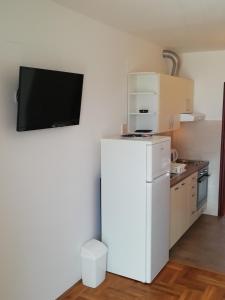 a white refrigerator in a kitchen with a tv on the wall at APARTMANI JURIĆ in Trpanj
