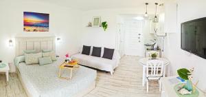 ein Wohnzimmer mit einem weißen Sofa und einem Fernseher in der Unterkunft EL ESTUDIO DE LA PLAYA BENALBEACH Vistas al Mar in Benalmádena