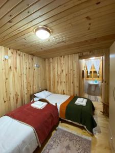 two beds in a room with wooden walls at Avusor mola cafe pansiyon in Çamlıhemşin