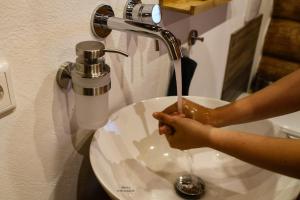 a person drinking water from a bathroom sink at Holzhaus Wildsbergblick in Beiseförth